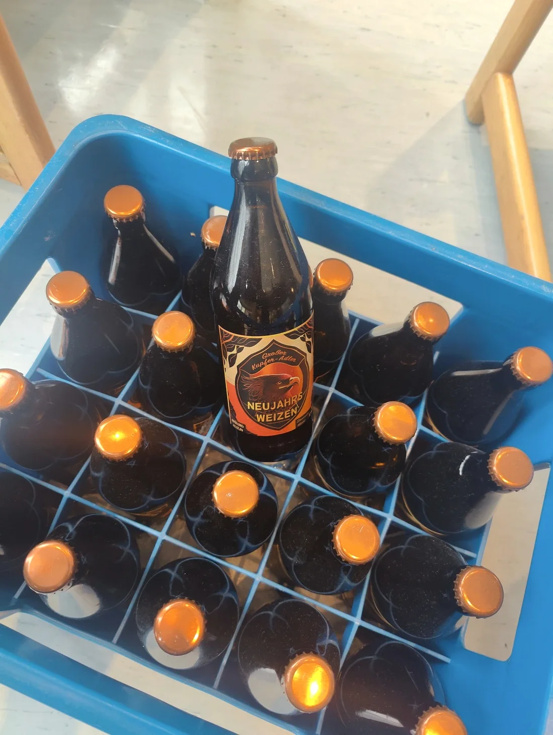 Neujahrs-Weizen von Großer Kupfer-Adler: eine Flasche ragt aus einer Kiste voller Bügelflaschen.